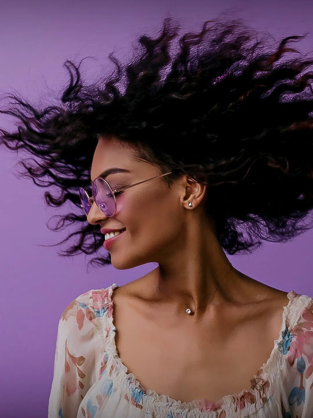 Modelo sorrindo com cachos pretos ao vento
